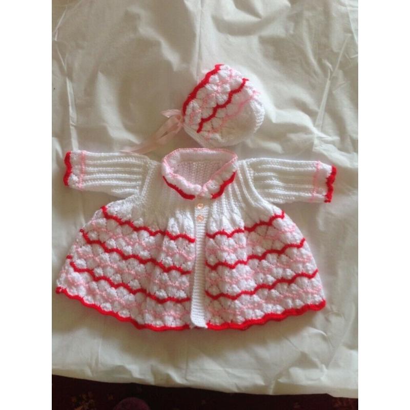 Hand knitted baby cardigan & bonnet, shown made with white, pink & red wool.